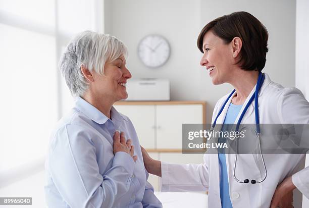 doctor reassuring patient, in examination room - sala-de-reconocimiento-médico fotografías e imágenes de stock