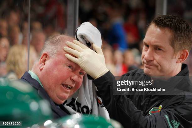 Minnesota Wild head coach Bruce Boudreau is treated by a member of the training team after being struck by a puck during the game against the...