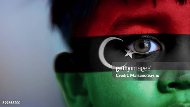 boy's face, looking at camera, cropped view with digitally placed libya flag on his face. - lebanon country stock pictures, royalty-free photos & images