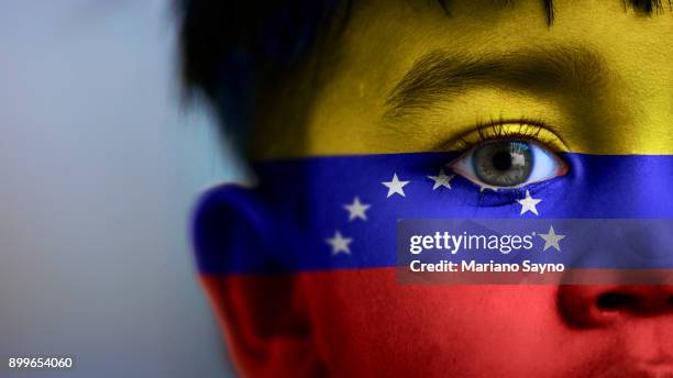 boy's face, looking at camera, cropped view with digitally placed venezuela flag on his face. - venezuela flag stock pictures, royalty-free photos & images