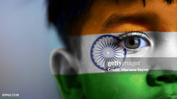 boy's face, looking at camera, cropped view with digitally placed india flag on his face. - india independence stock pictures, royalty-free photos & images