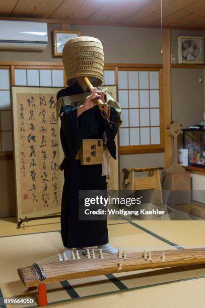 Japanese man in traditional monks outfit in Kyoto, Japan, is playing a traditional Japanese shakuhachi, a Japanese end-blown flute.