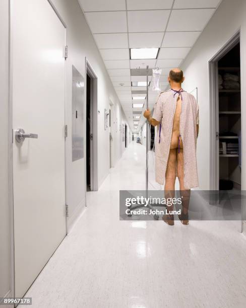 patient in gown standing in long hospital hallway. - hospital gown imagens e fotografias de stock