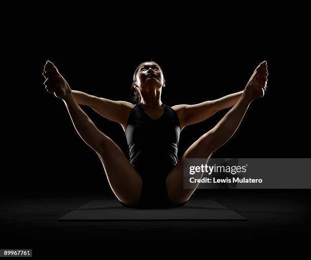woman practicing yoga in seated angle position - piernas separadas fotografías e imágenes de stock