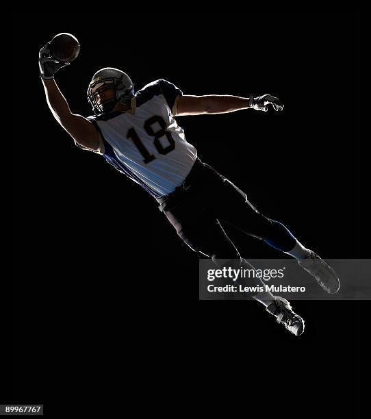 american football player leaping to catch ball - wide receiver athlete stockfoto's en -beelden