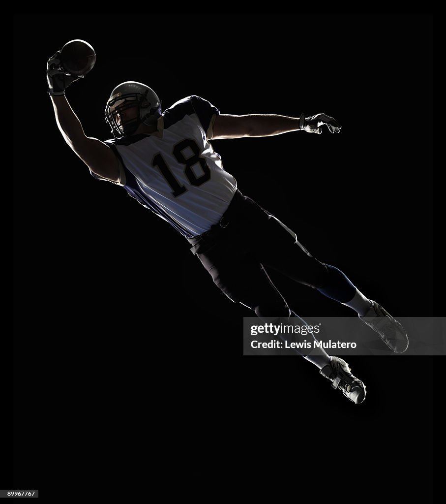 American Football player leaping to catch ball