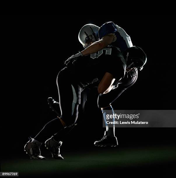 american football player tackling opponent - tackling photos et images de collection