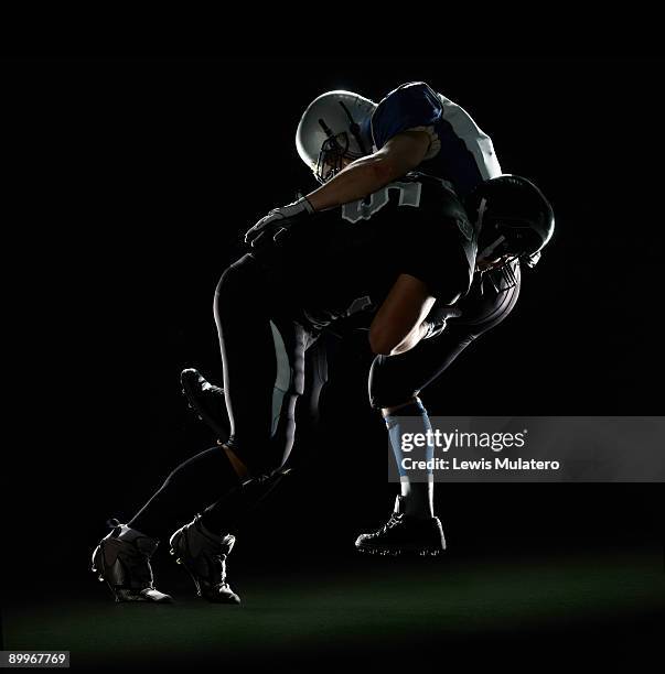american football player tackling opponent - placcare foto e immagini stock