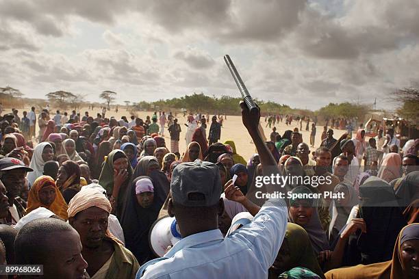 Security officer keeps order for hundreds of people desperate to move to a less crowded refugee camp in Dadaab, the world�s biggest refugee complex...