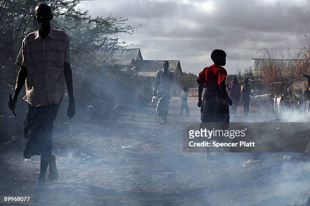 People walk through burning refuse in Dadaab, the world�s biggest refugee complex August 20, 2009 in Dadaab, Kenya. The Dadaab refugee complex in...