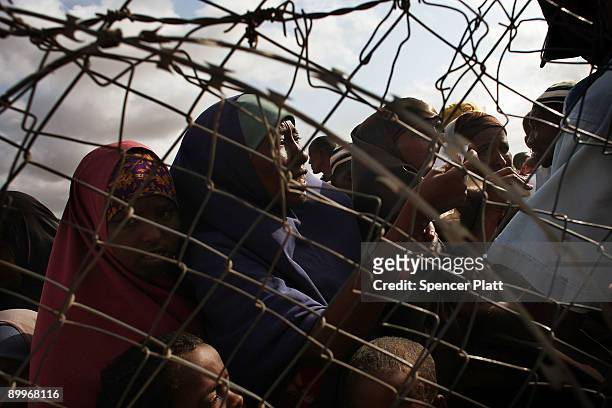 Refugees desperate to move to a less crowded refugee camp stand behind a United Nations fence in Dadaab, the world�s biggest refugee complex August...