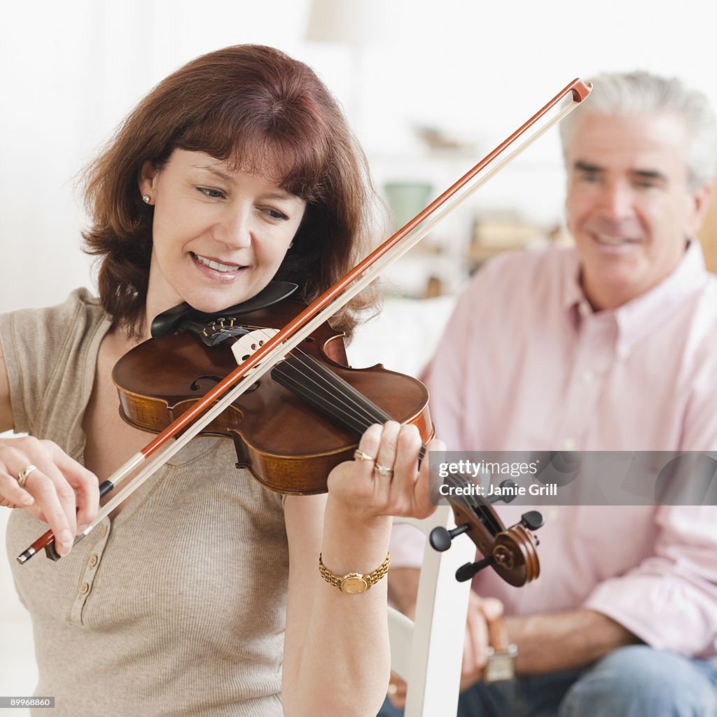 Woman playing violin while husband watches