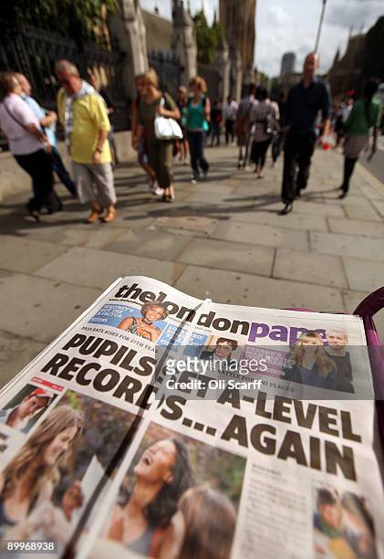 Members of the public walk past copies of The London Paper, a free evening newspaper owned by News International, in front of the Houses of...