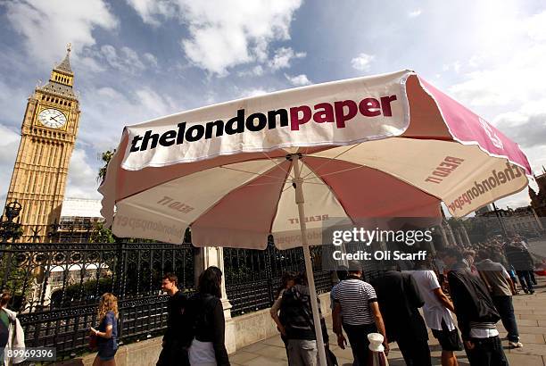 Parasol for The London Paper, a free evening newspaper owned by News International, marks a distribution point in front of the Houses of Parliament...