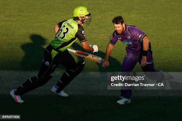 Jos Butler of the Sydney Thunder takes a run as Dan Christian of the Hobart Hurricanes chases the ball during the Big Bash League match between the...