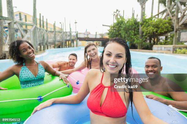 multi-ethnic group of adult friends on inflatable rings - lazy river stock pictures, royalty-free photos & images