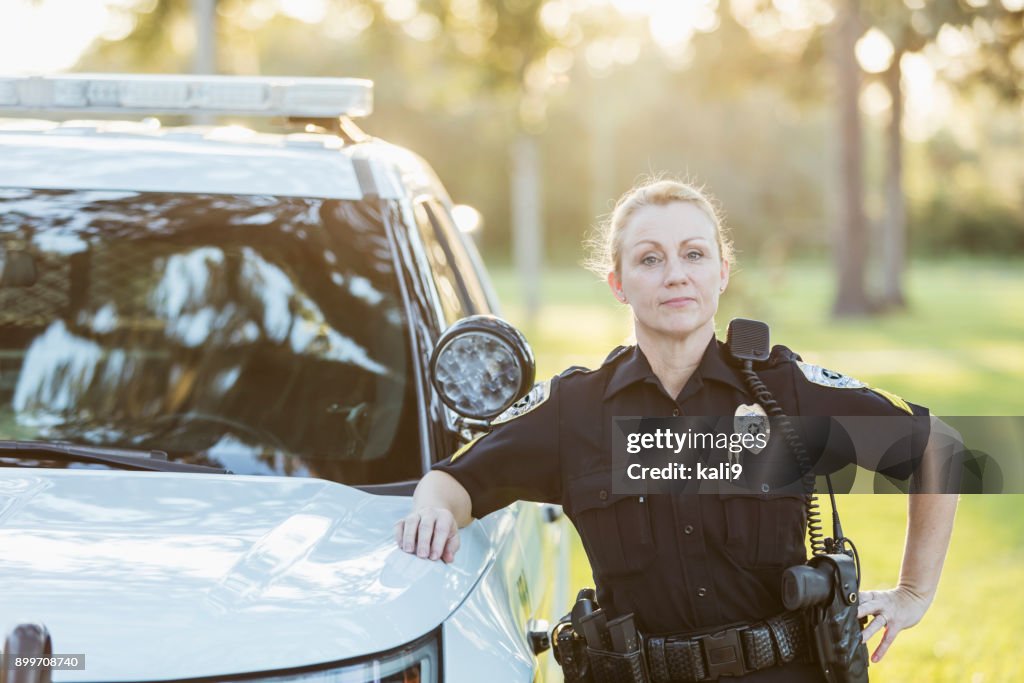 Policewoman standing beside police squad car