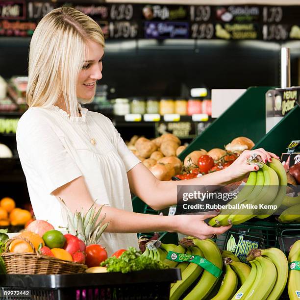 woman buying produce at the supermarket - bananen supermarkt stock-fotos und bilder