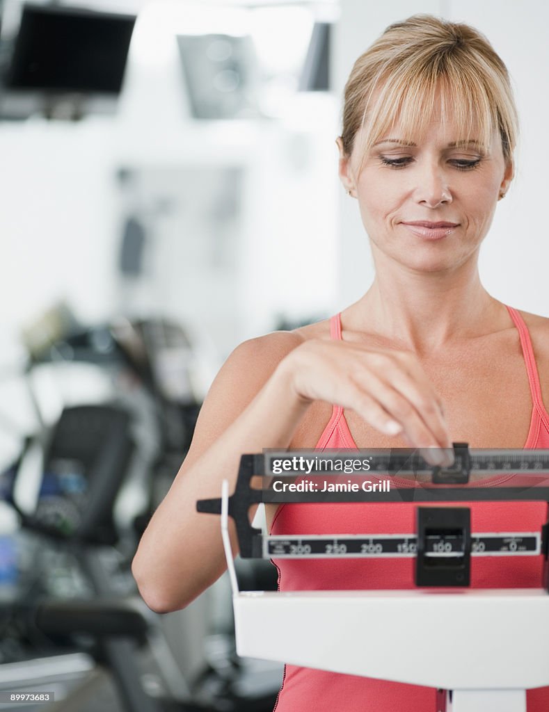 Woman weighing herself at gym