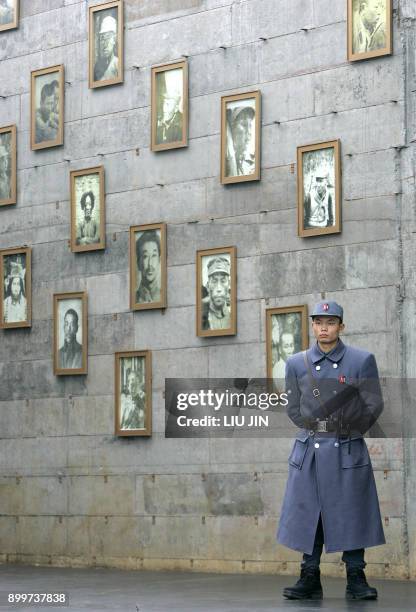 Security official stands beside portraits of prisoners of war at the Anti-Japanese War Museum in Dayi county in China's southwestern province of...