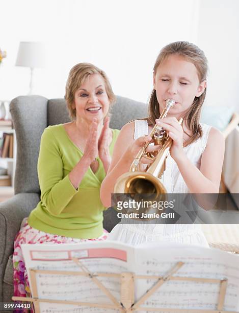 young girl playing trumpet for grandmother - トランペット ストックフォトと画像