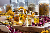 Bottles of essential oil with dried rose petals, chamomile, calendula and frankincense