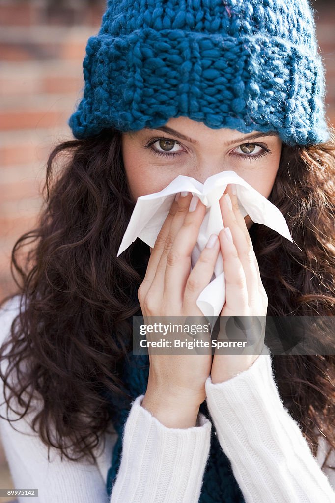 Young woman wiping nose