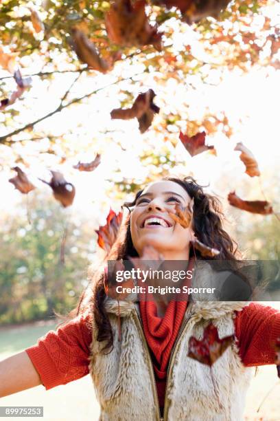 young woman playing with leaves - zorgeloos stockfoto's en -beelden
