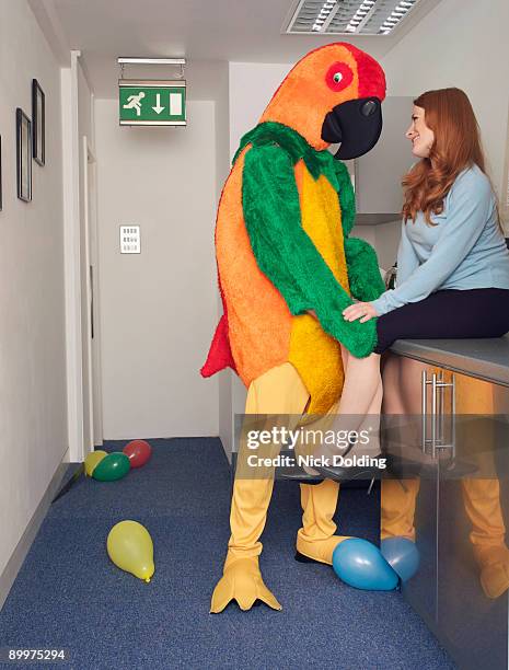 man in parrot outfit with co worker - funny dressed man stock-fotos und bilder