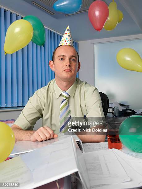 grumpy office worker in party hat - overdoing stock pictures, royalty-free photos & images