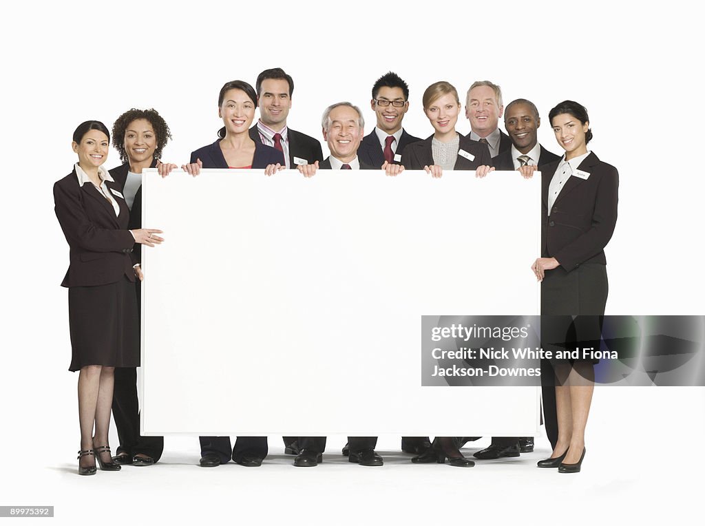 A business group holding a white board