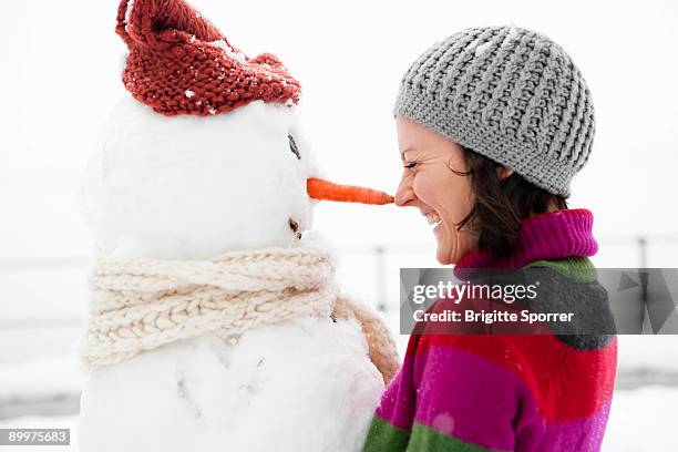 woman nose to nose with snowman - snowman stock-fotos und bilder