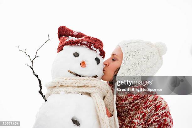 woman kissing snowman - frau schneemann stock-fotos und bilder