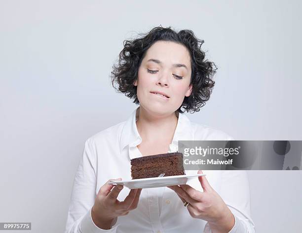 woman looking at plate of cake - temptation stock-fotos und bilder