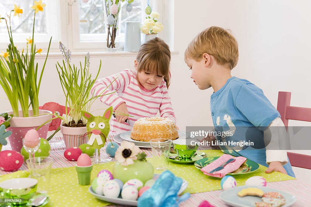 Girl and boy cutting cake easter table