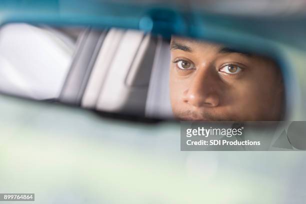 partial reflection of man looking in rear view mirror - looking from rear of vehicle point of view stock pictures, royalty-free photos & images