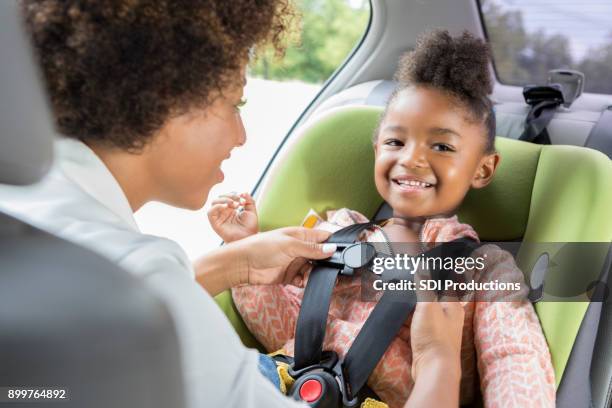 meisje glimlacht als ze is verbogen in autostoel - safety harness stockfoto's en -beelden