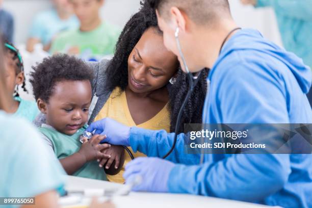 baby boy grabs medical volunteer's stethoscope during exam - child reaching stock pictures, royalty-free photos & images