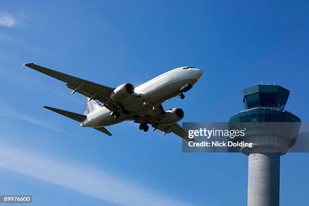 plane flying past control tower - torre de control de circulación aérea fotografías e imágenes de stock