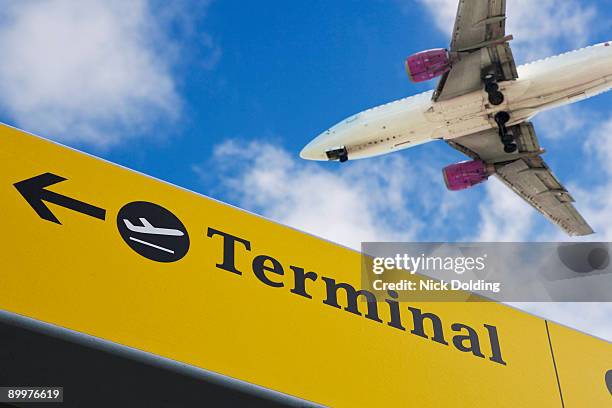 plane flying over 'terminal' sign - stansted airport 個照片及圖片檔