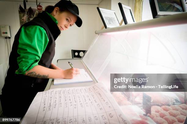 a young female butcher writing the tasks - metzgerin stock-fotos und bilder