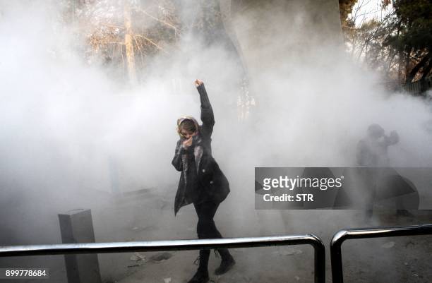 An Iranian woman raises her fist amid the smoke of tear gas at the University of Tehran during a protest driven by anger over economic problems, in...