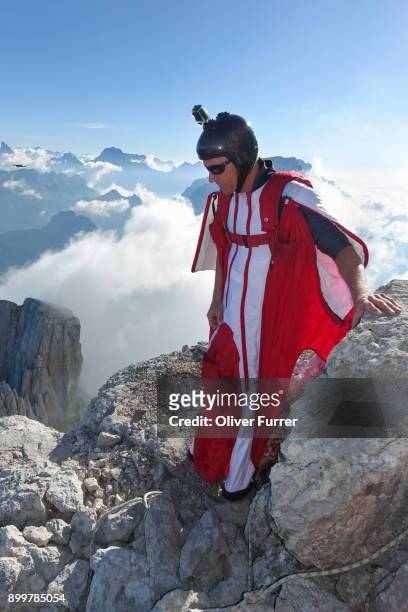 male wingsuit base jumper preparing to fly from cliff edge - confidence male landscape stock-fotos und bilder