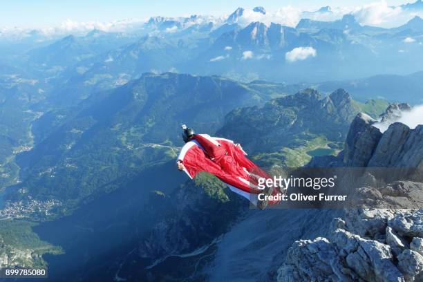 male wingsuit base jumper taking off from cliff edge - confidence male landscape stock-fotos und bilder