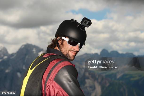 portrait of base jumper wearing wingsuit with action camera on helmet, dolomite mountains, canazei, trentino alto adige, italy, europe - base jumping imagens e fotografias de stock