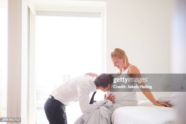 romantic man kissing pregnant girlfriends stomach in bedroom - jakob helbig stock pictures, royalty-free photos & images