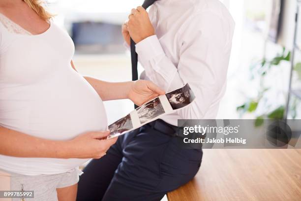 mid section of pregnant young woman looking at ultrasound pictures - jakob helbig fotografías e imágenes de stock