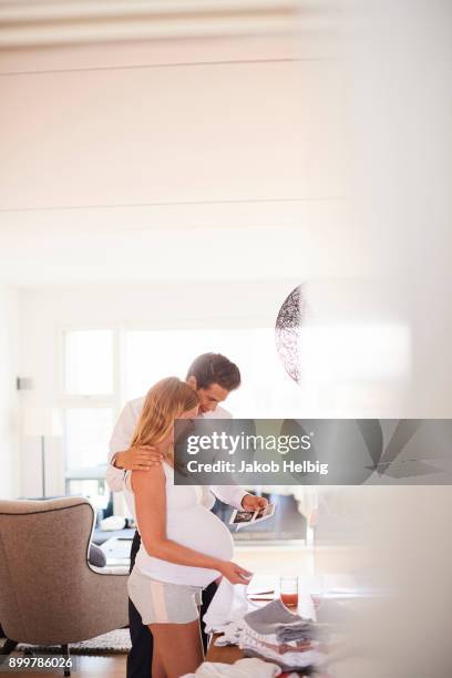 pregnant couple looking at ultrasound pictures in living room - jakob helbig fotografías e imágenes de stock