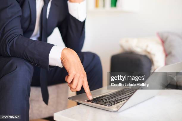 mid section of businessman sitting on armchair using laptop - jakob helbig stock pictures, royalty-free photos & images