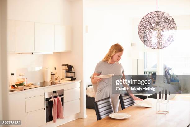 pregnant young woman in laying the dining table - jakob helbig fotografías e imágenes de stock